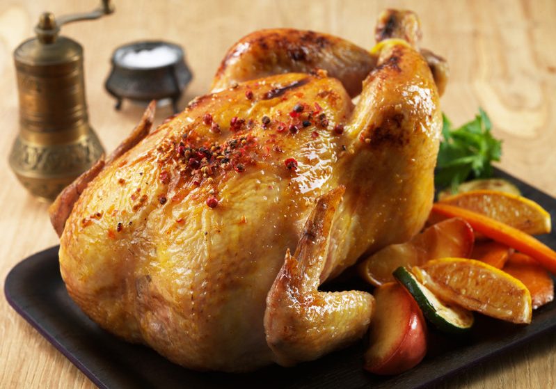 Roast chicken and various vegetables on wooden plate